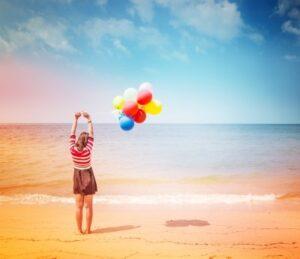 girl with balloons on shore