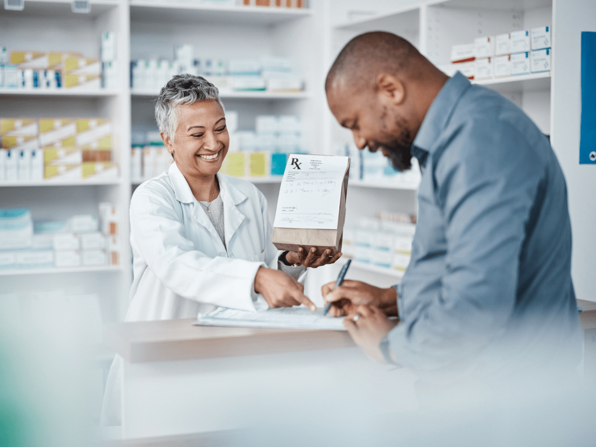 pharmacist helping patient as he signs forms.